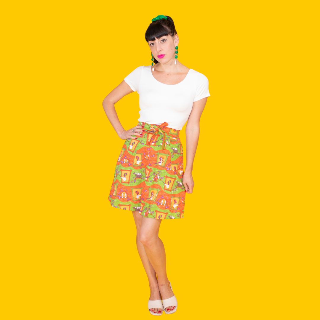 Dark-haired girl in white shirt and orange and green print skirt with tie waist