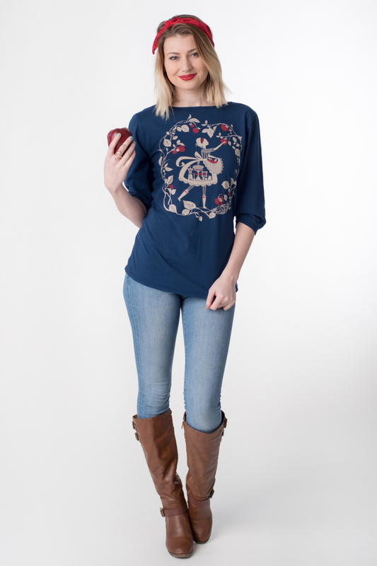 Model wearing navy blue 3/4 sleeve tee with print of an apple picking girl and red apples