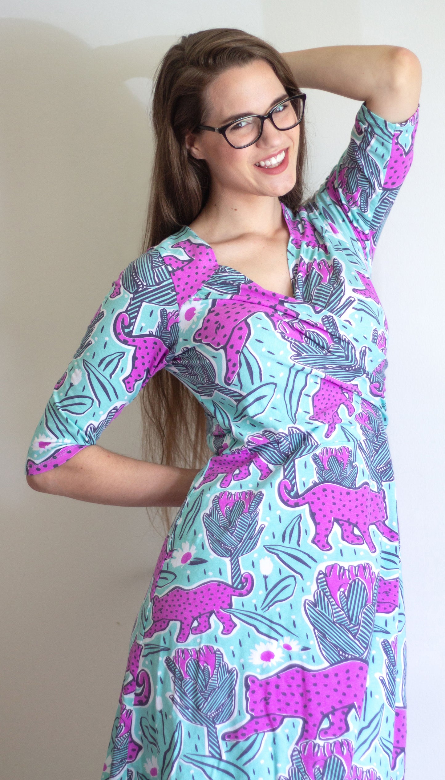 Orchid pink and mint green jaguar and protea flower print wrap dress with sleeves on long-haired model