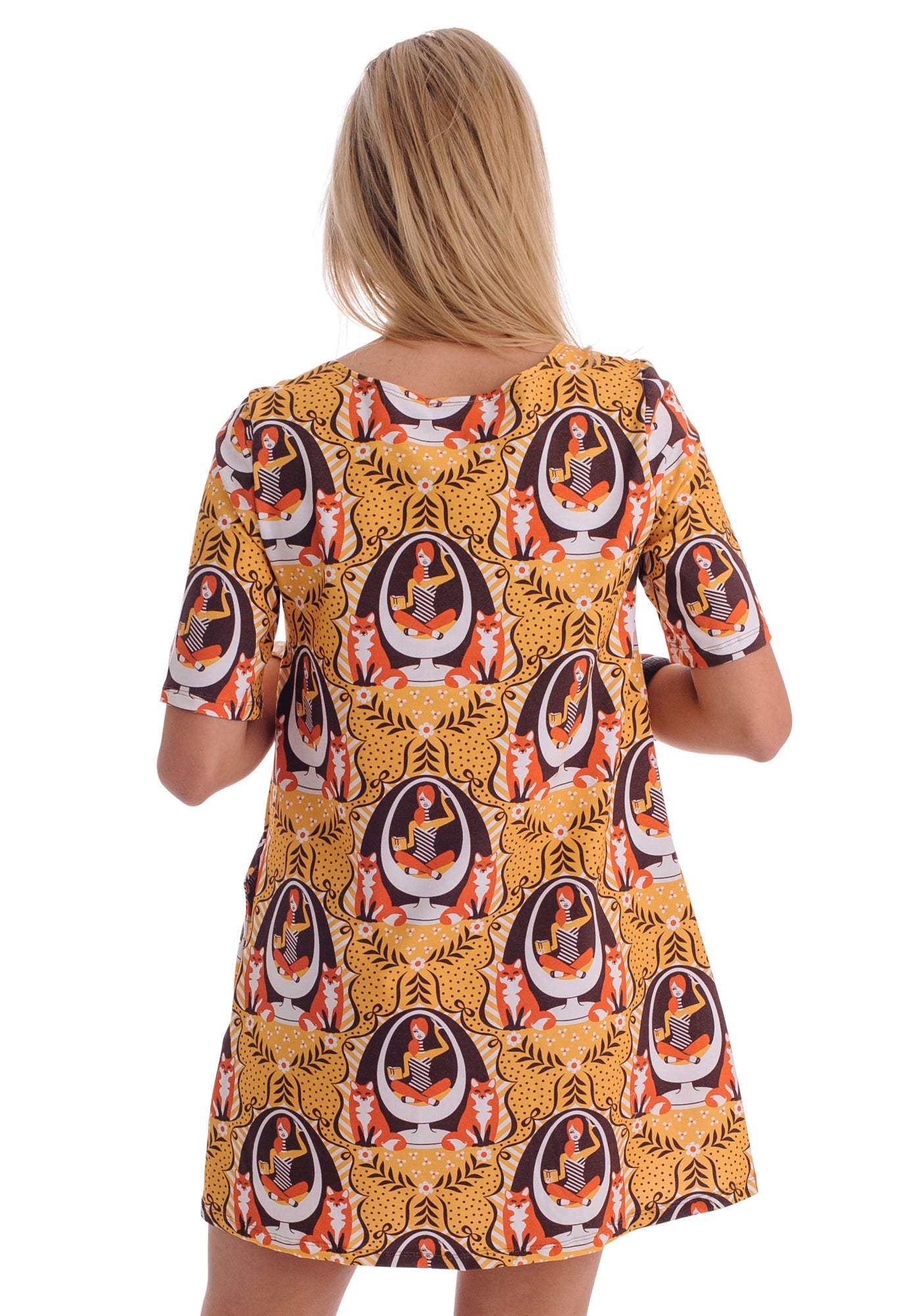Back view of mustard yellow pocket tunic featuring print of foxes and girls reading books sitting in an egg chair