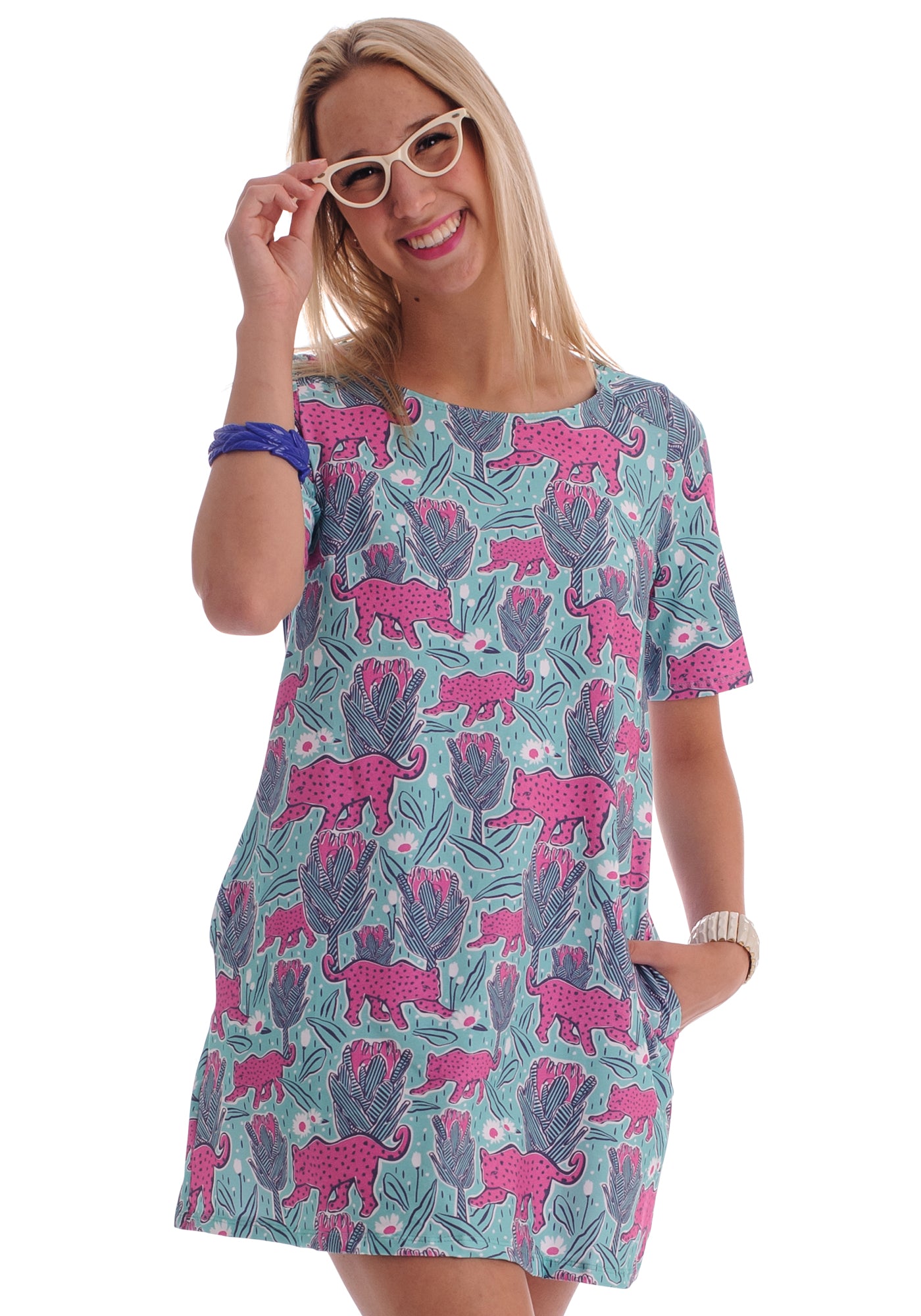 Blonde haired model with glasses in mint green and pink pocket tunic with a print of protea flowers and jaguars