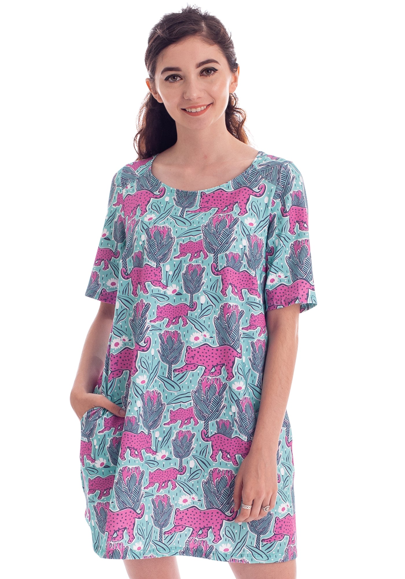 Dark haired model in mint green and pink pocket tunic with a print of protea flowers and jaguars