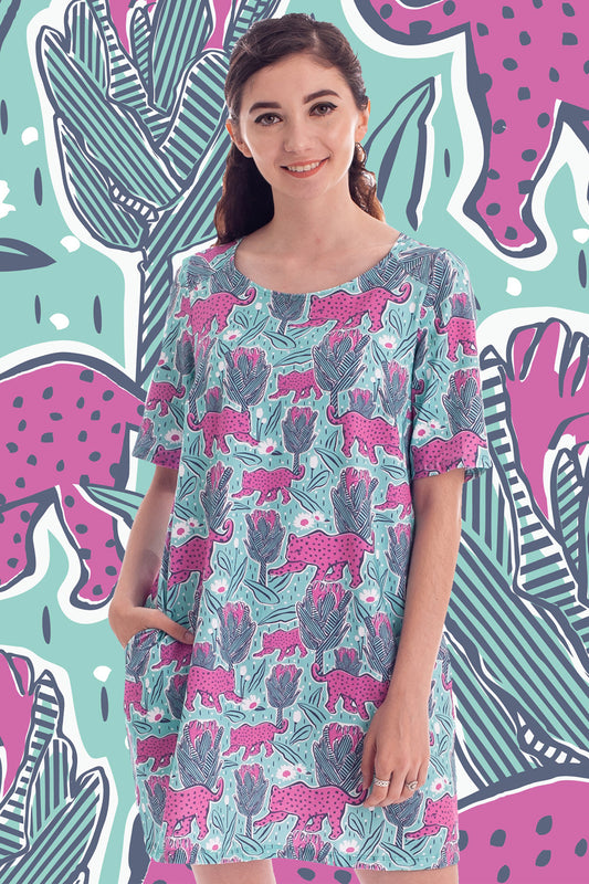 Dark haired model in mint green and pink pocket tunic with a print of protea flowers and jaguars