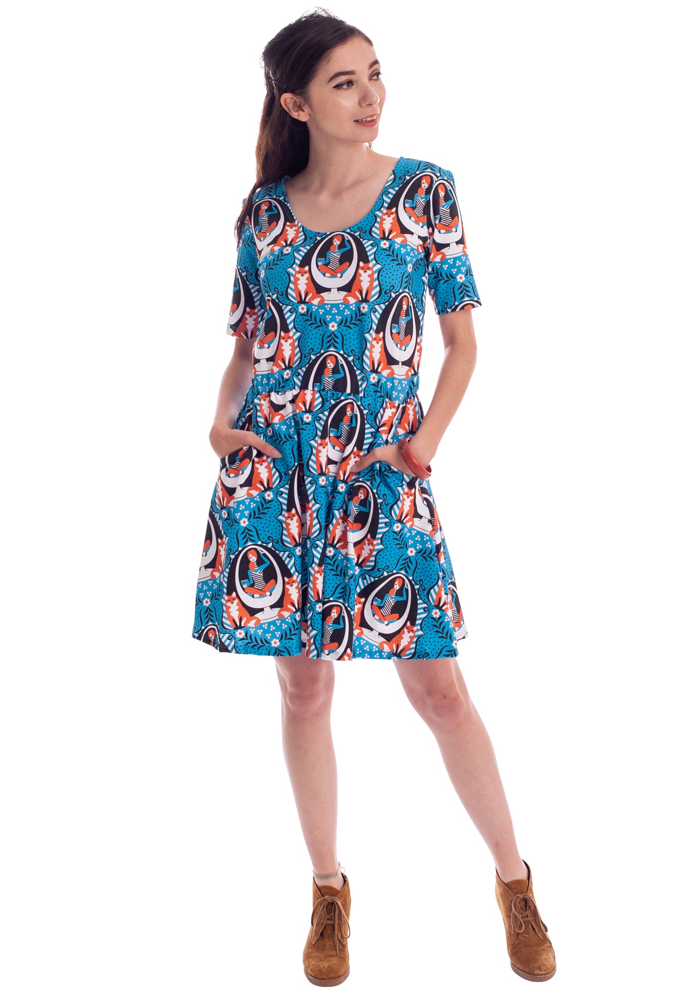 Dark haired model wearing bright blue dres with graphic of redhead girl sitting in egg chair flanked by two foxes