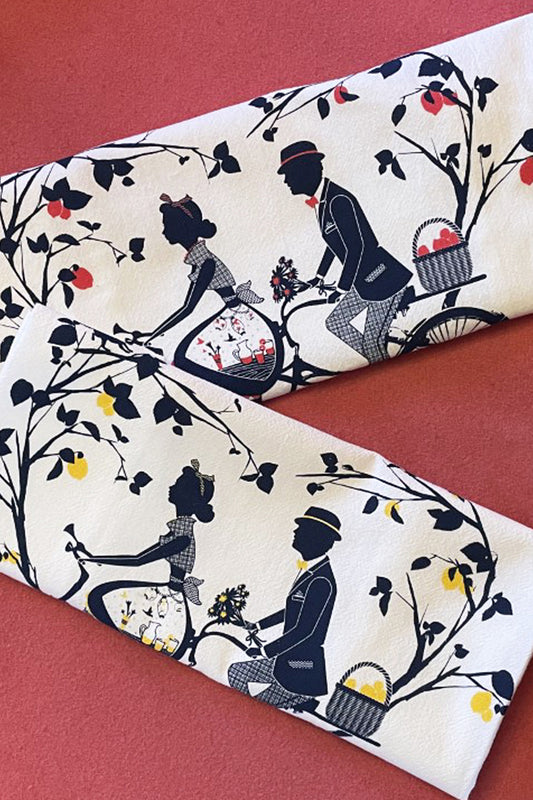 Two tea towels featuring an older couple riding a tandem bicycle