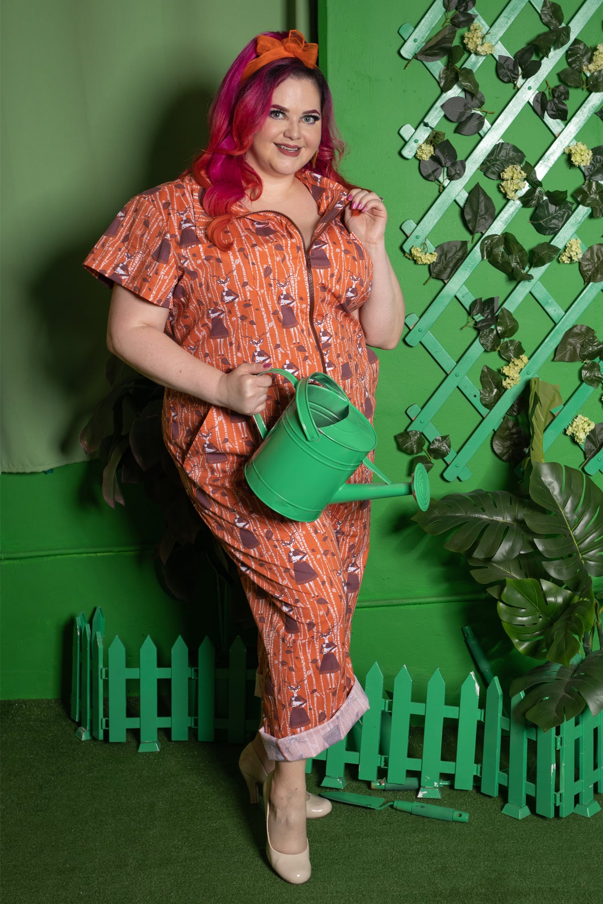Fun young woman in orange and brown jumpsuits with pockets and printed with deer, girls and trees