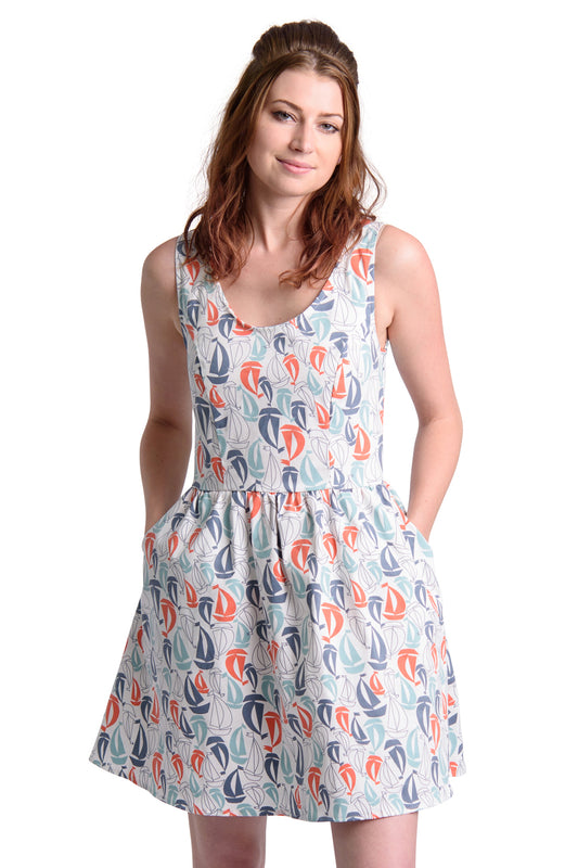 Model in white fit and flare dress with red and blue sailboat print and pockets