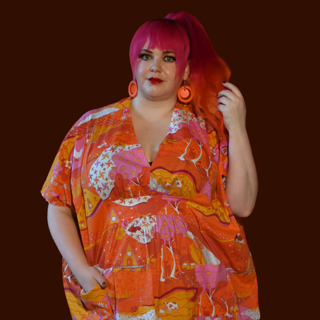 Pink haired model wearing dress featuring landscape in pink, yellow and orange
