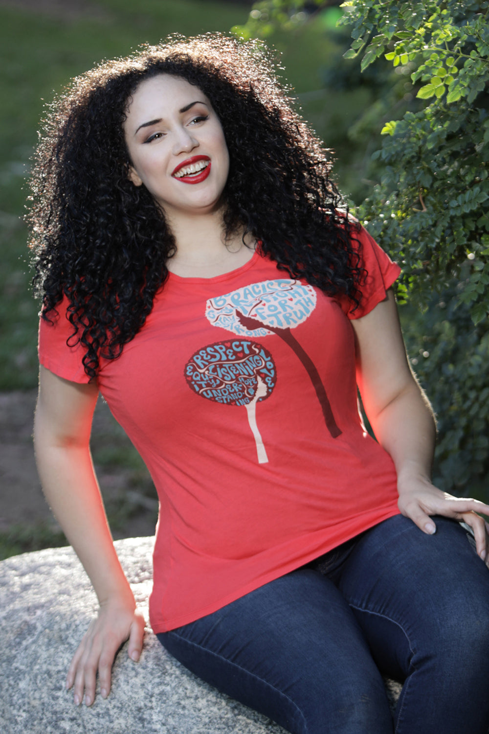 Model wearing red tee with graphic of dandelion made up of inspiring words