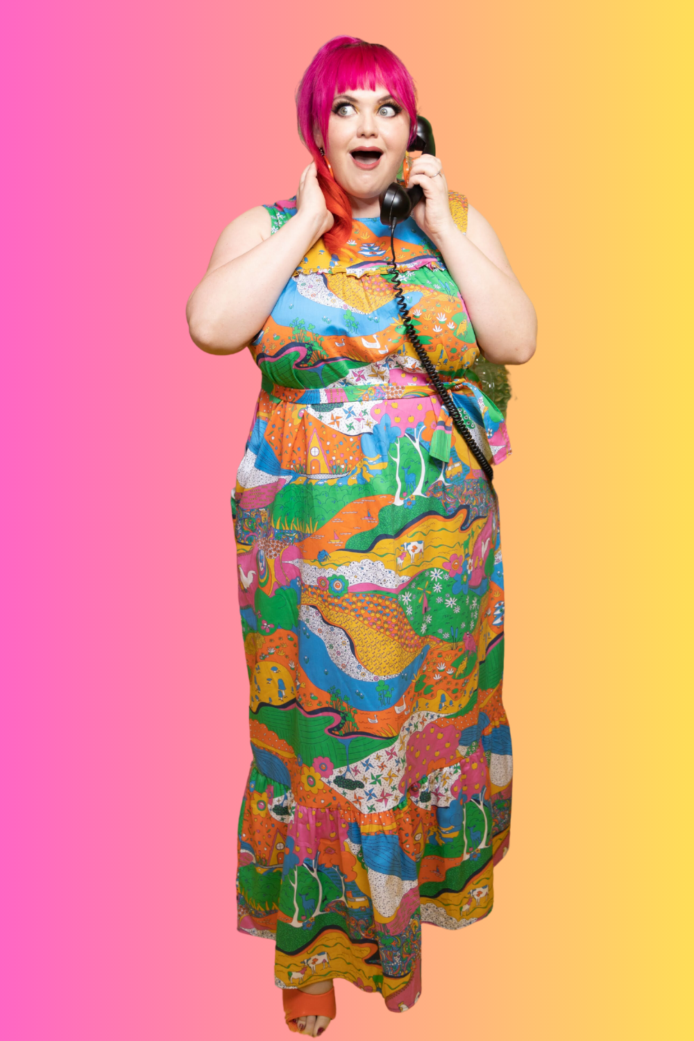 Radiant pink haired model wearing rainbow colored psychedelic maxidress, talking on phone with colorful background