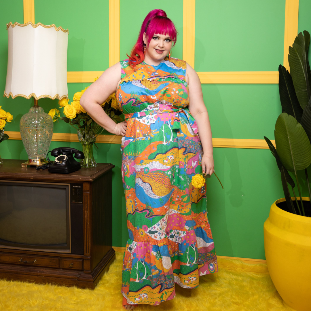 Radiant pink haired model wearing rainbow colored psychedelic maxidress in colorful room