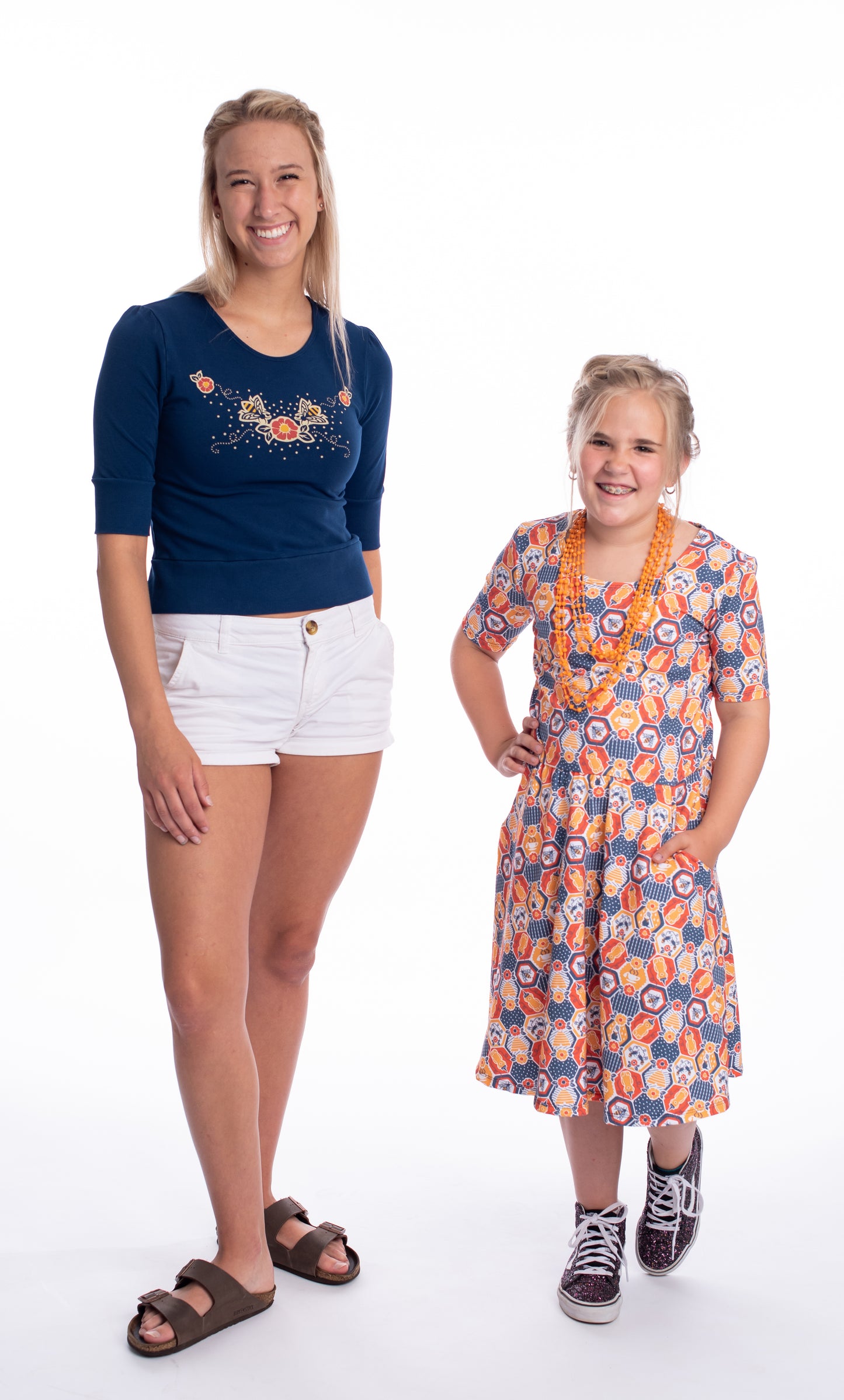 Navy blue scoop neck cropped French terry top with print of bees and flowers on blonde model with child in fun geometric dress