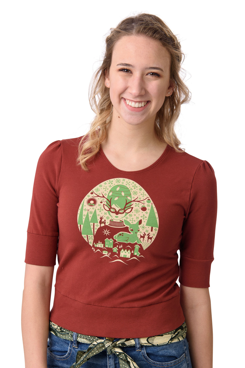 Rust- colored cropped French terry tee with bright green and off white screen print of masked girl with reindeer, trees and snowflakes