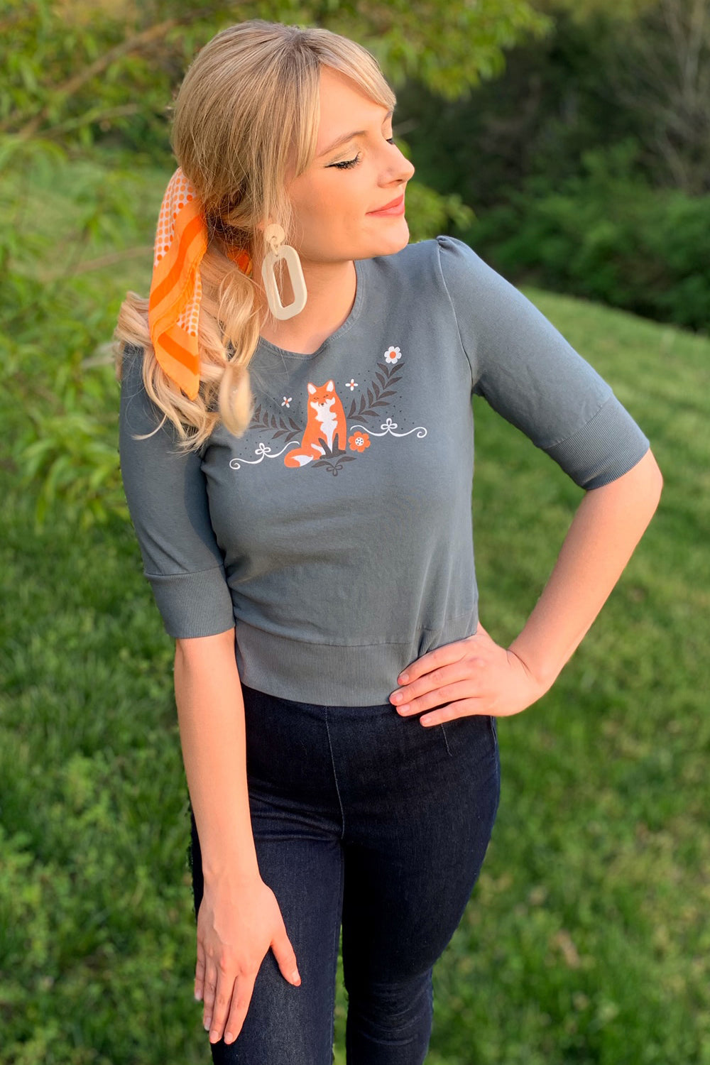 Model wearing grey 1/2 sleeve tee with graphic of a fox and flowers