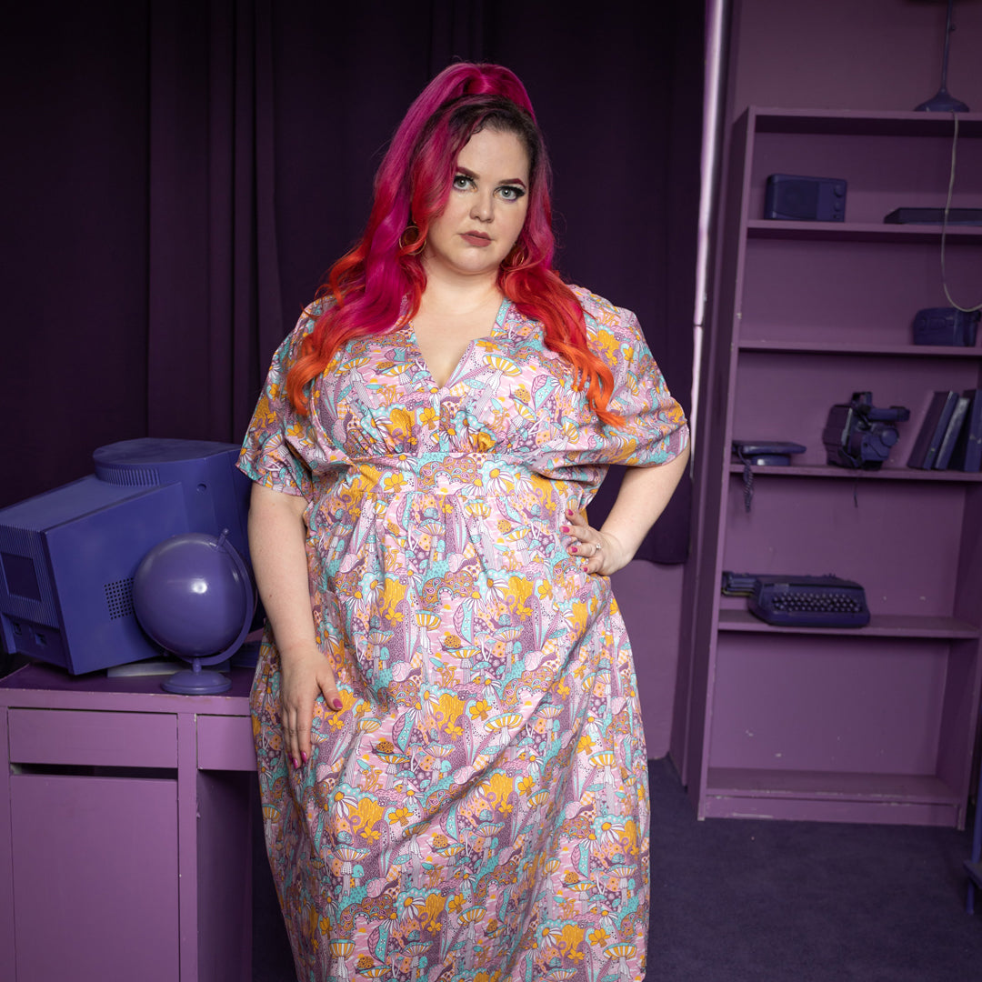 Pink v-neck mushroom, flower and snail print maxi caftan on pink-haired model in purple room