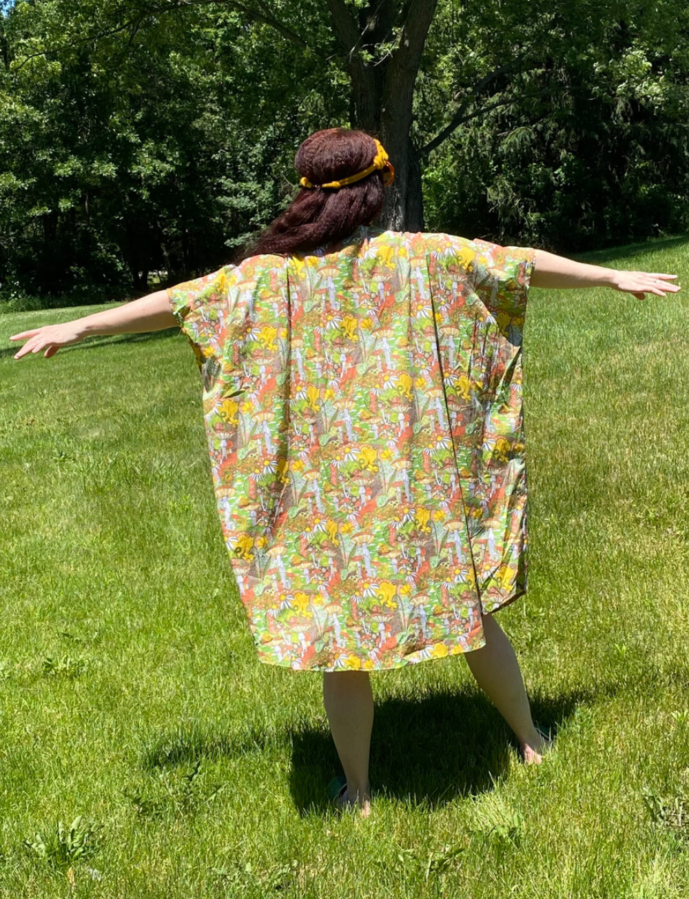 Back view of green, orange, and yellow mushroom, snail and flower print cotton caftan
