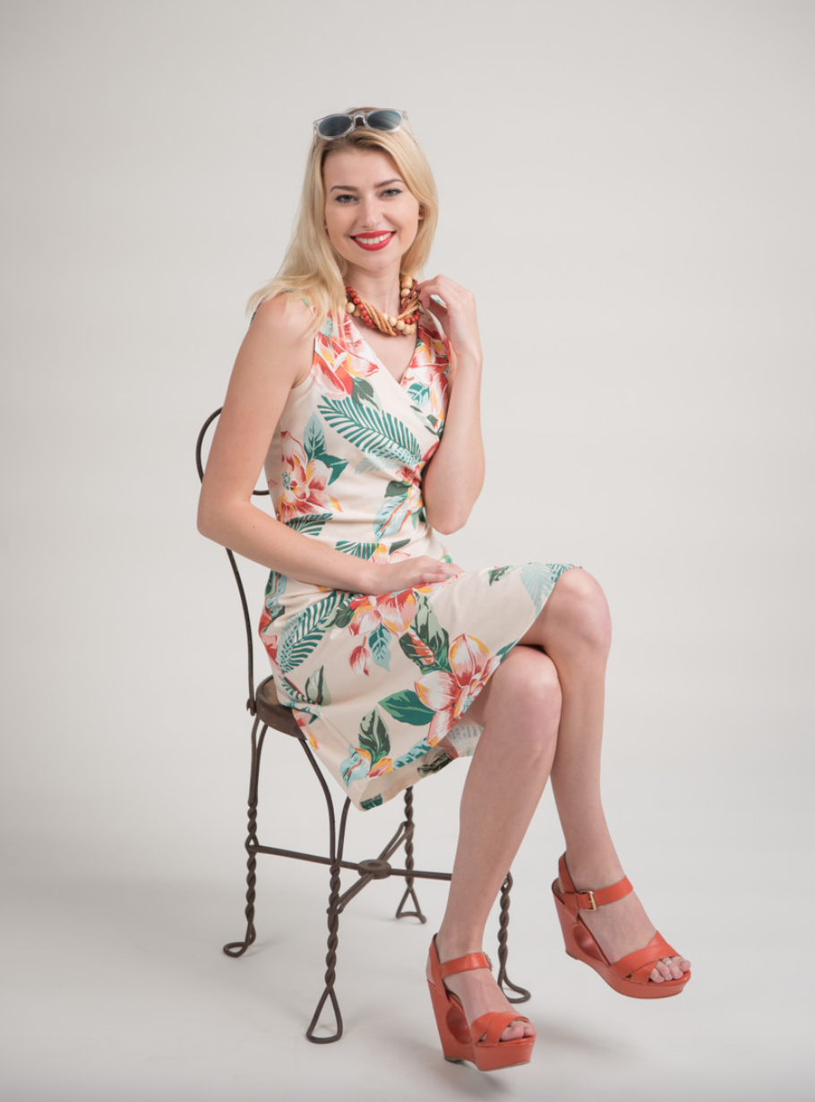 Pretty blonde girl wearing polynesian wrap dress and seated in a chair