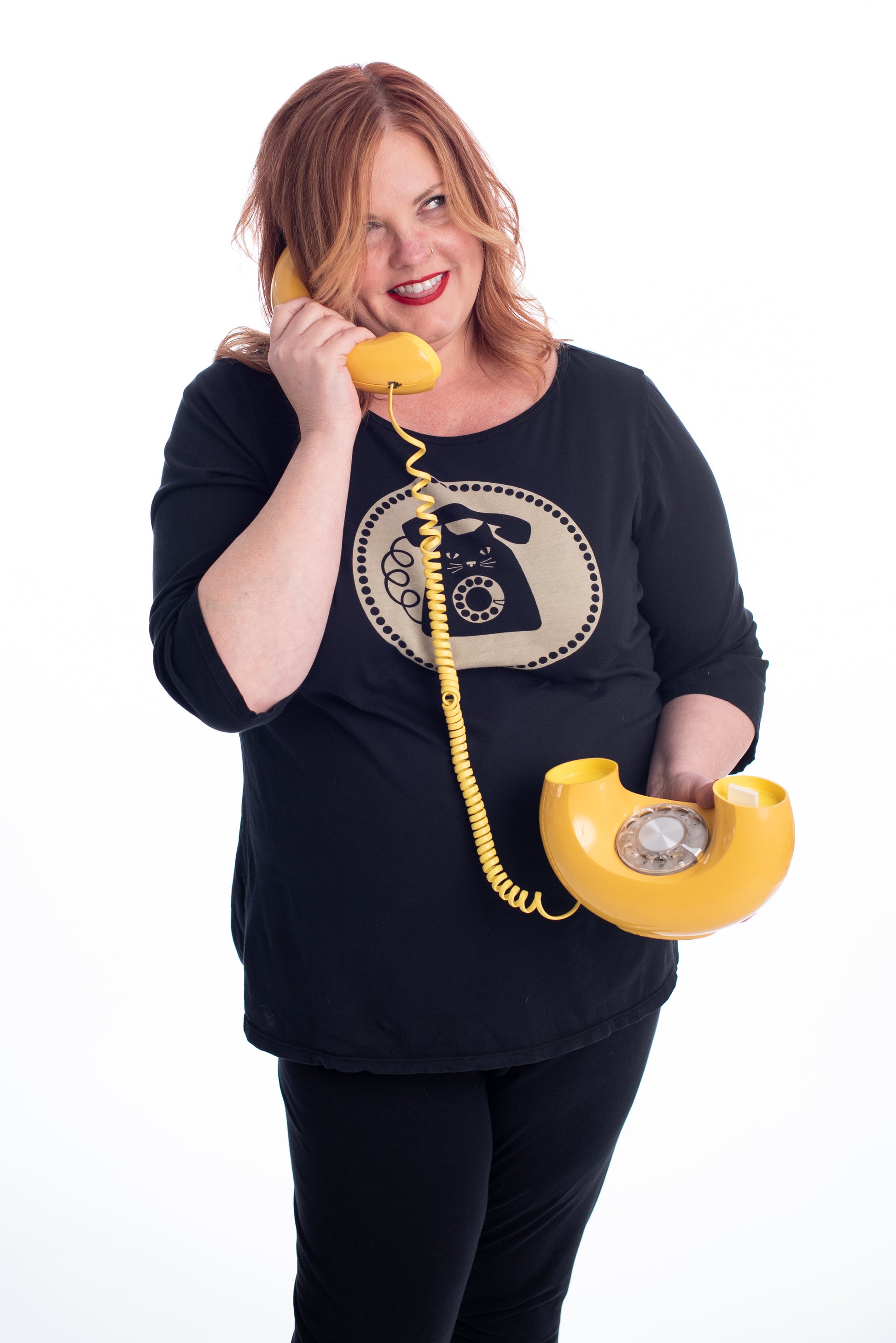 Red haired plus size model talking on donut phone while wearing black cat phone graphic 3/4 sleeve tee