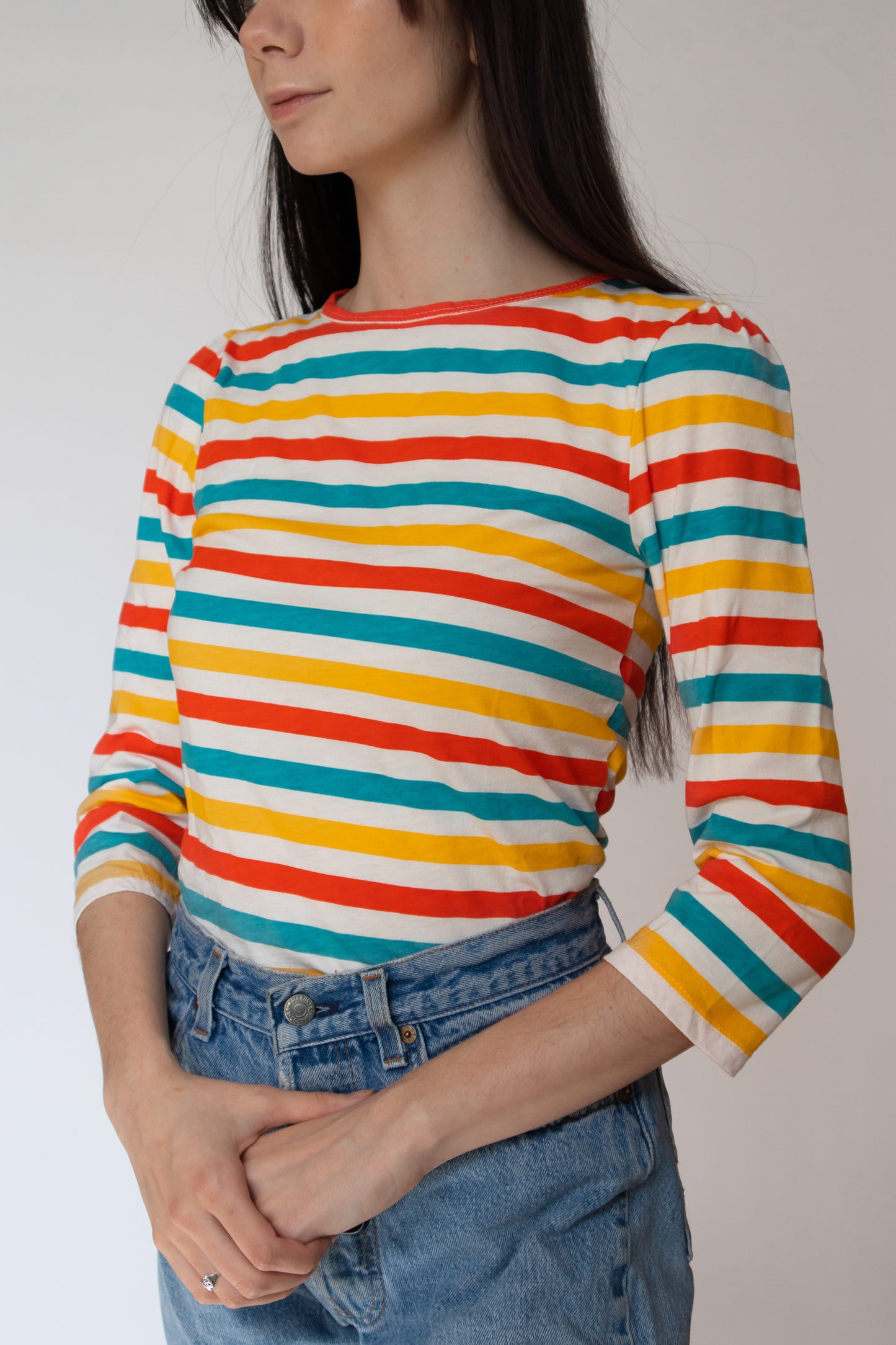 Closeup of bright orange, yellow and blue 3/4 sleeved striped shirt with jeans