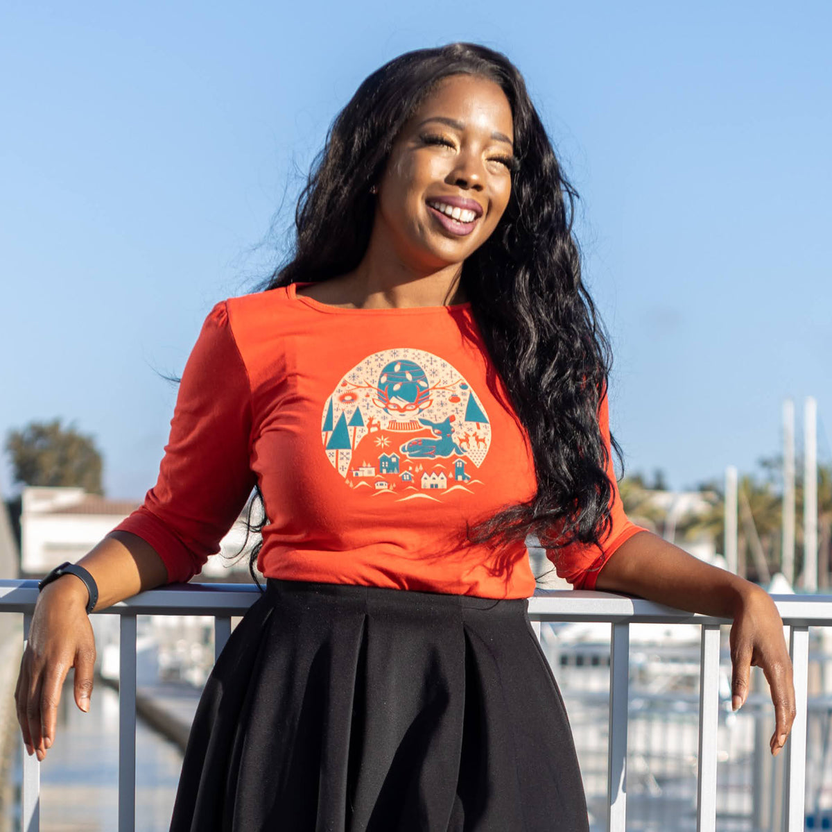 Bright red 3/4 sleeve Christmas tee with print of festive girl with beehive hair, reindeer, putz houses, snowflakes and pine trees