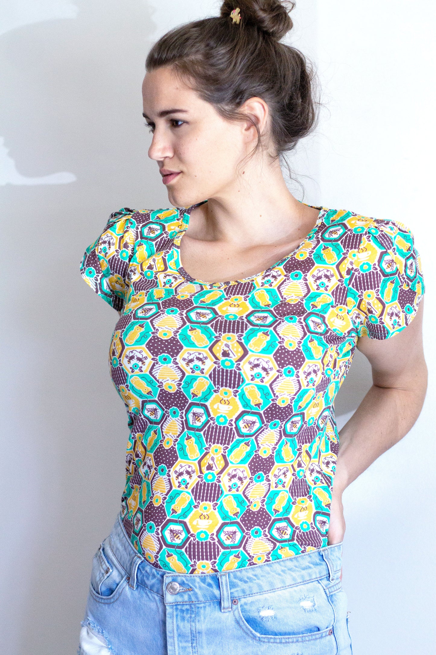 Green, yellow and brown honeycomb, bee and flower print tulip-sleeved tee on model 