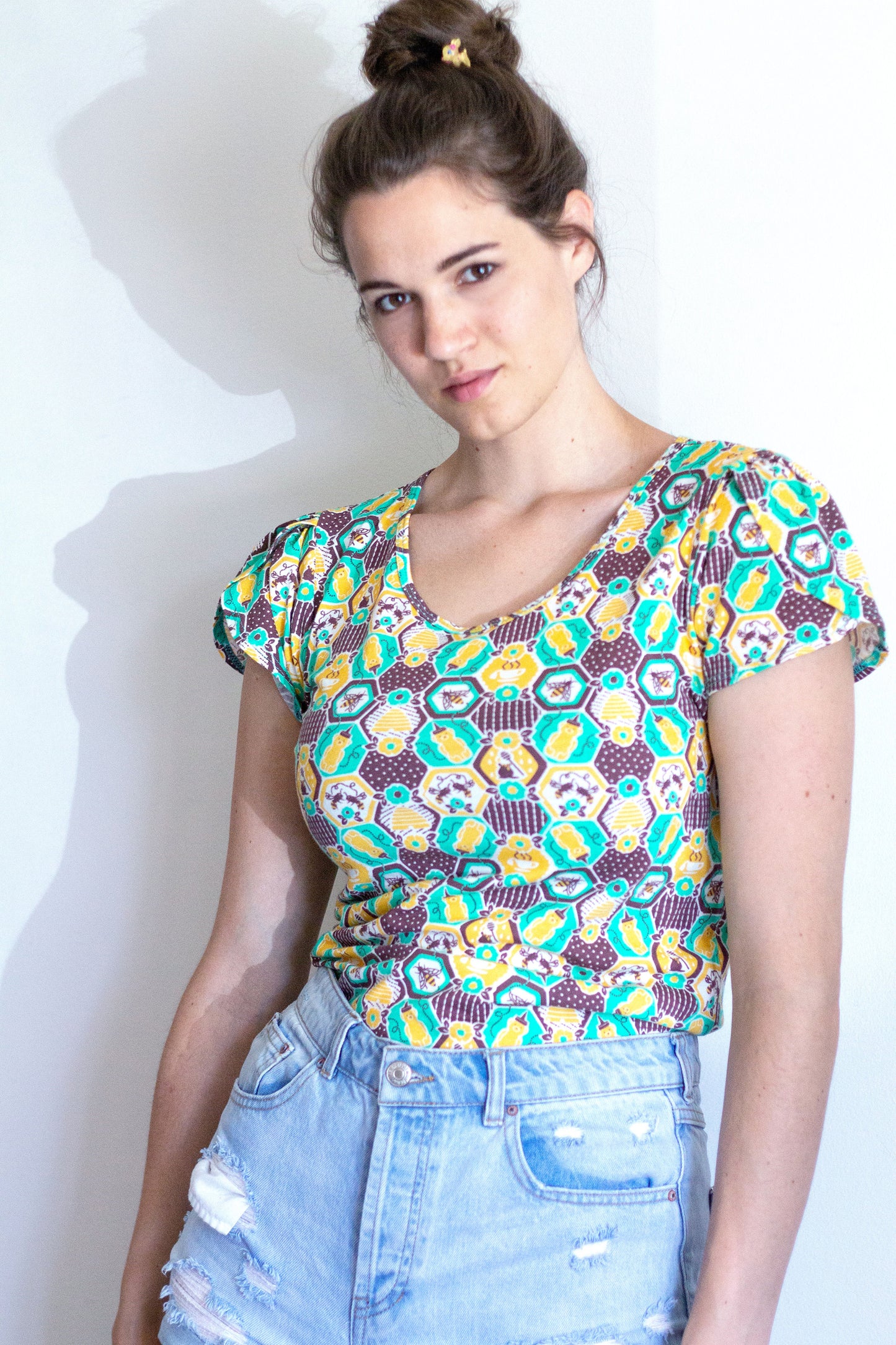 Green, yellow and brown honeycomb, bee and flower print tulip-sleeved tee on model 