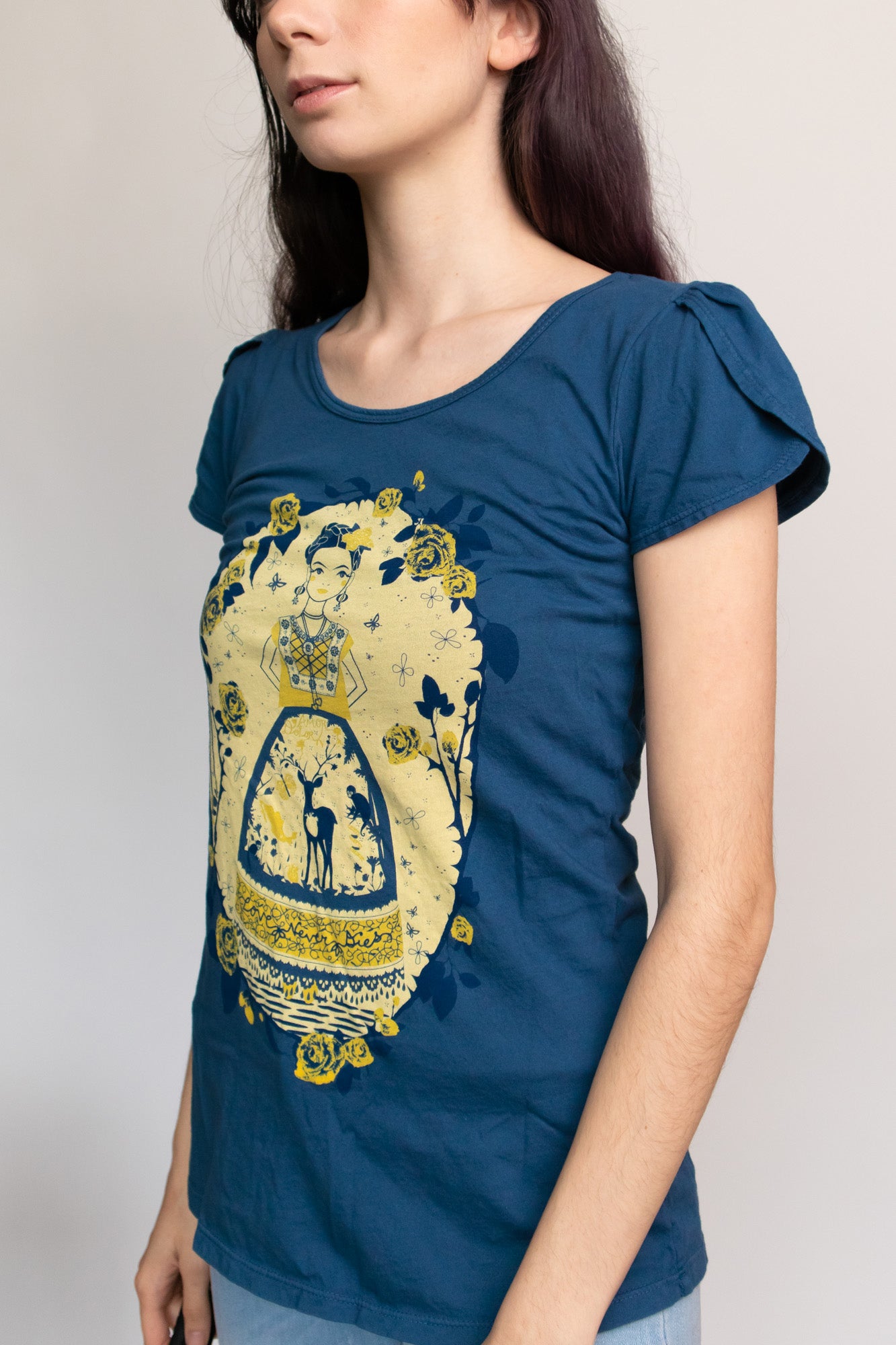 3/4 side view of navy blue tulip-sleeved tee with yellow and blue screen print of an artist woman, deer, and roses