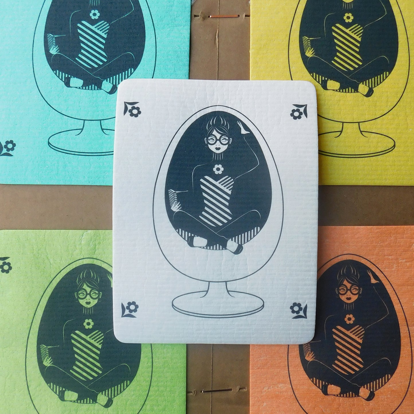 5 colorful Swedish dishcloths featuring our design of a girl in glasses reading in a vintage egg chair