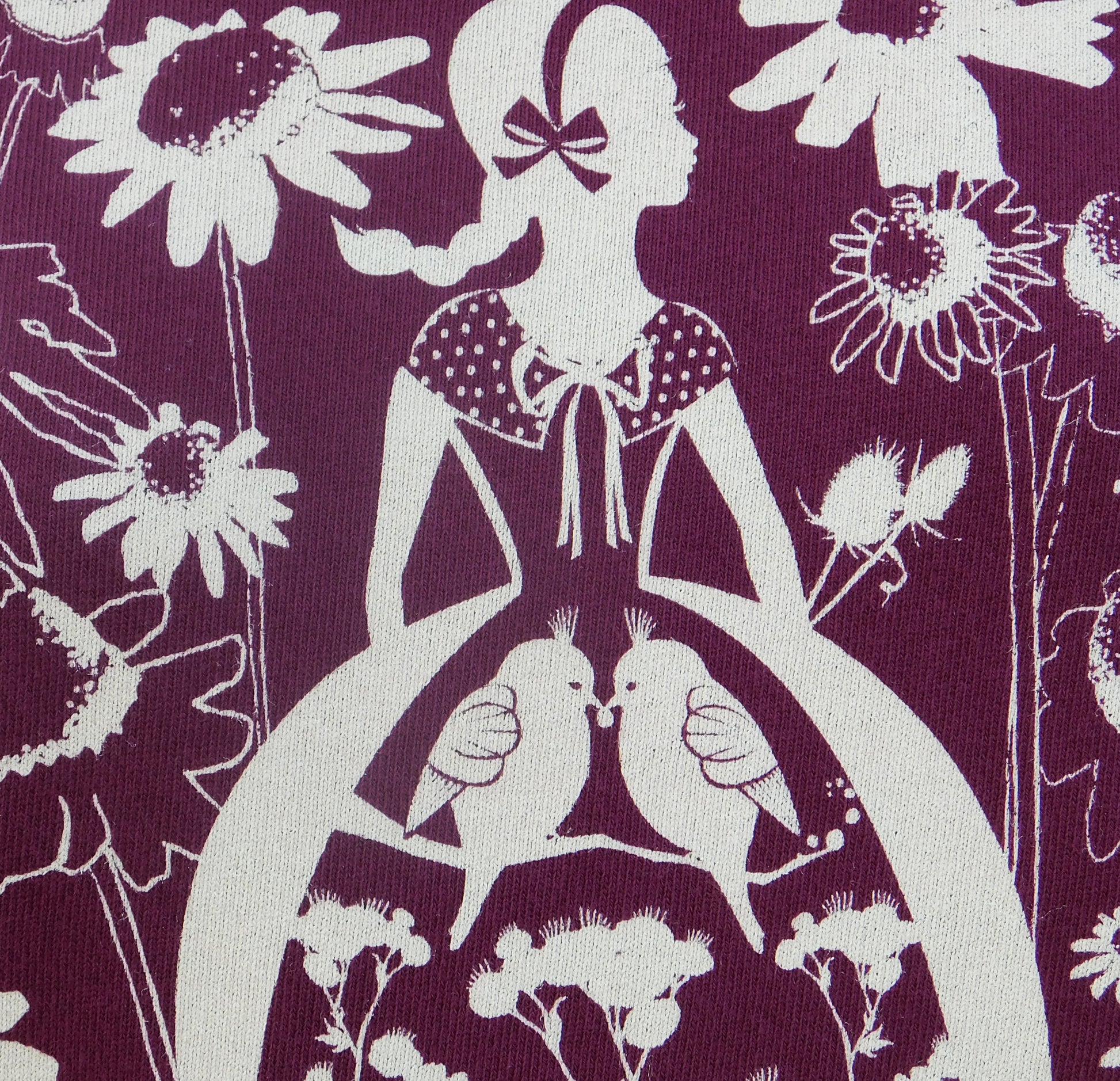 Closeup of plum sweatshirt with white screen print of cute girl surrounded by flora and fauna