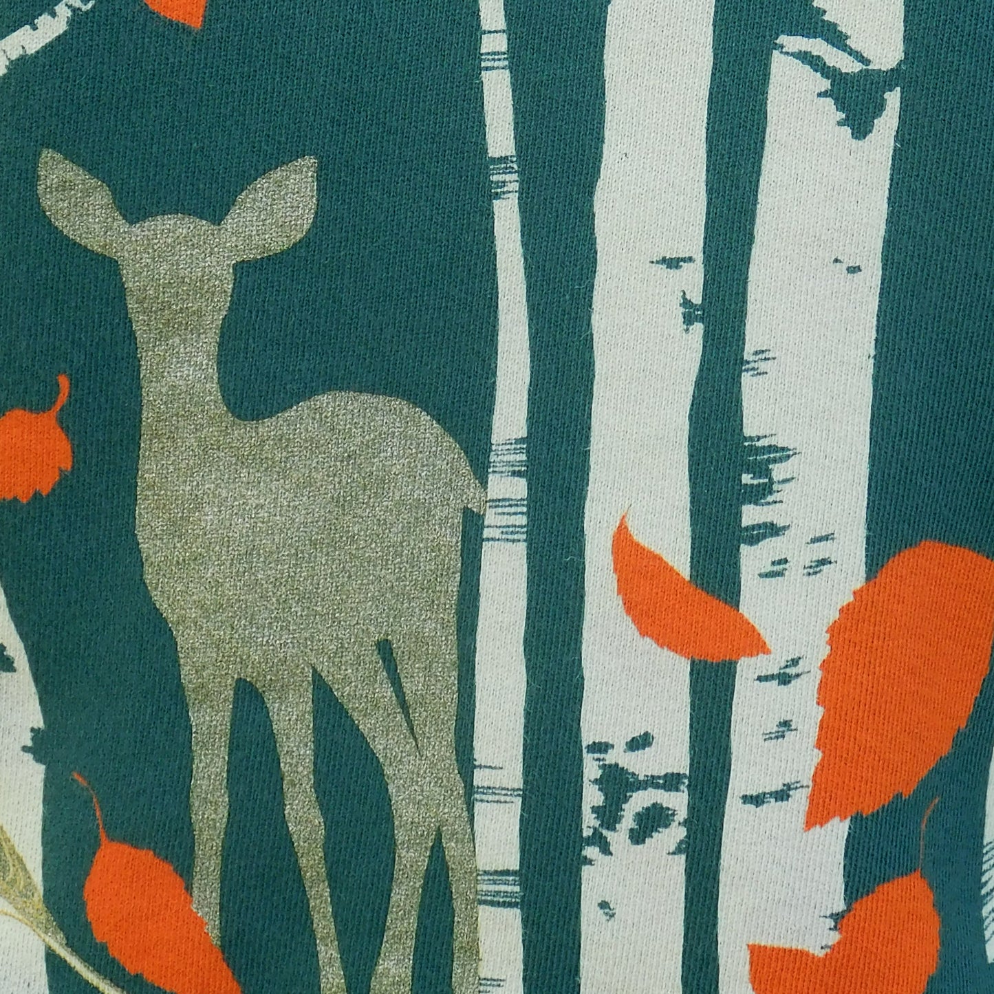 Closeup of dark green sweatshirt with screen print of birch trees, leaves, birds and deer