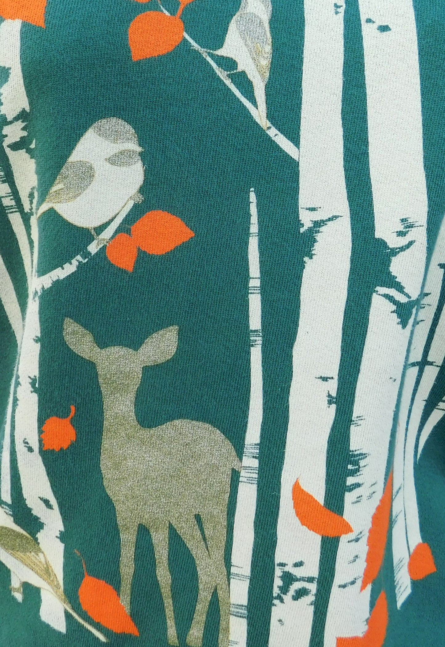 Closeup of dark green sweatshirt with screen print of birch trees, leaves, birds and deer