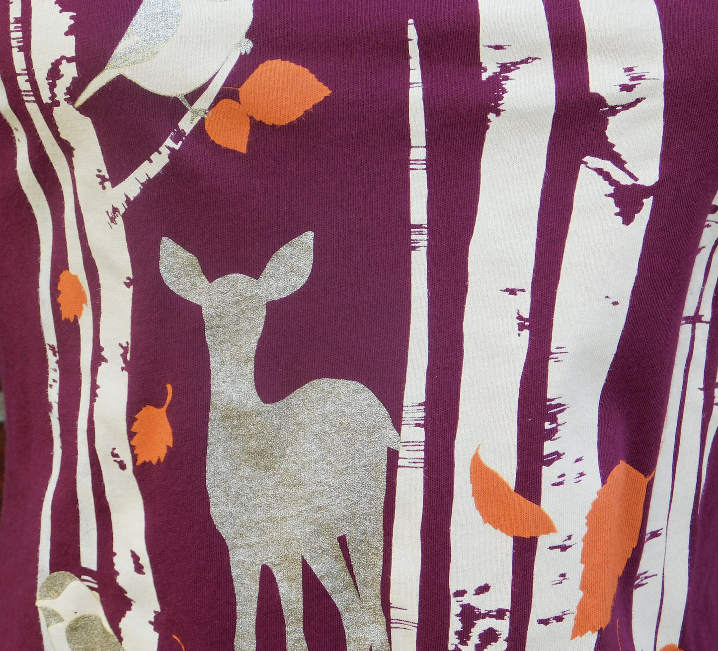 Closeup of plum sweatshirt with screen print of birch trees, leaves, birds and deer