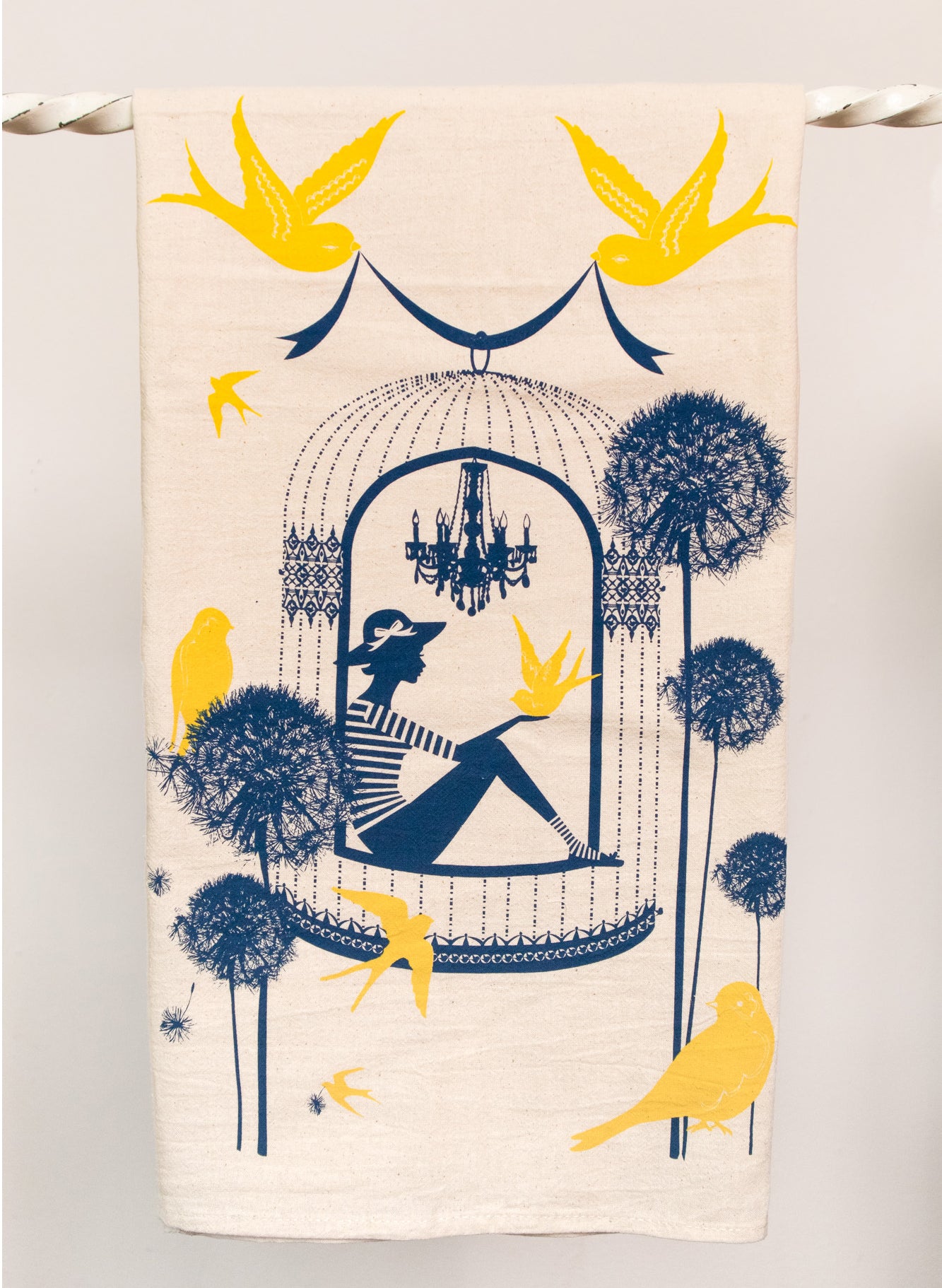 Cotton tea towel with yellow and navy print of a woman in a birdcage with birds and flowers