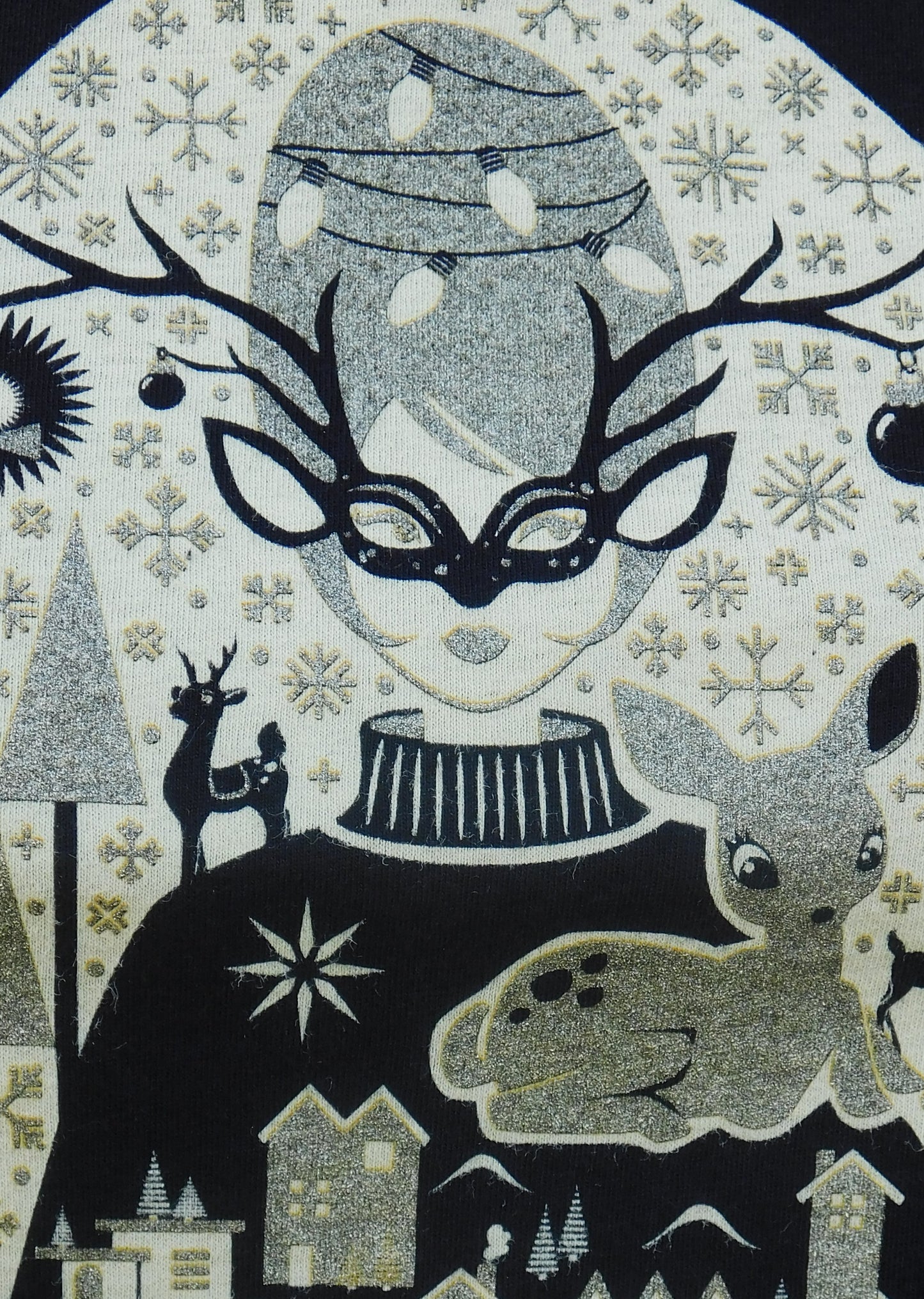 Closeup of gold, black and white design of masked girl with antlers, deer, and snowflakes