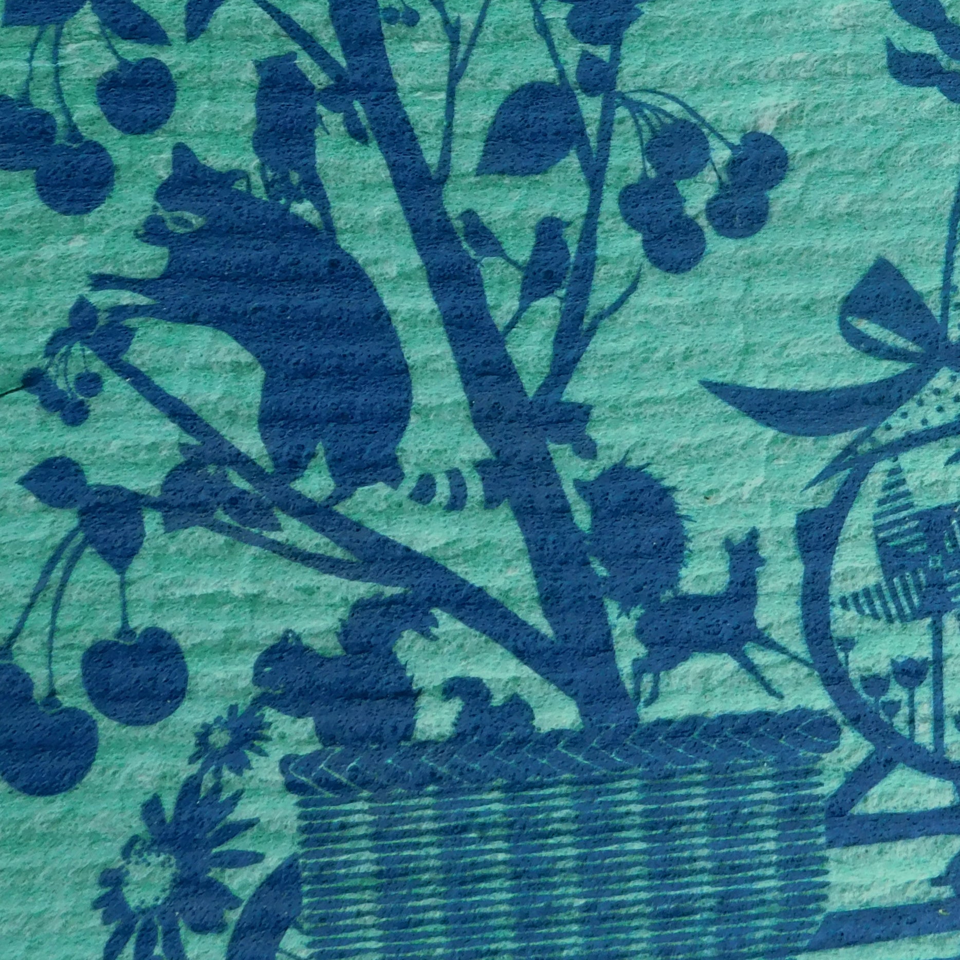 Closeup of blue Swedish dishcloth with dark blue graphic of woman riding a bike