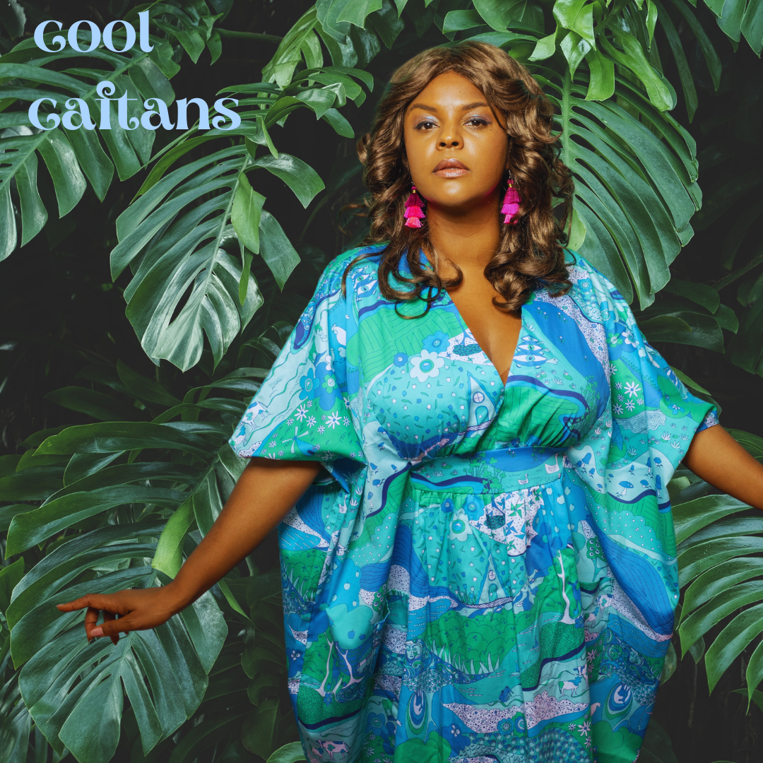 Pretty model in blue and green caftan in front of leaves with Cool Caftans caption