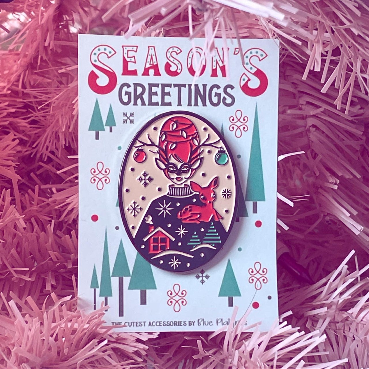 Bright vintage inspired red and green enamel pin of masked woman with beehive hair holding reindeer