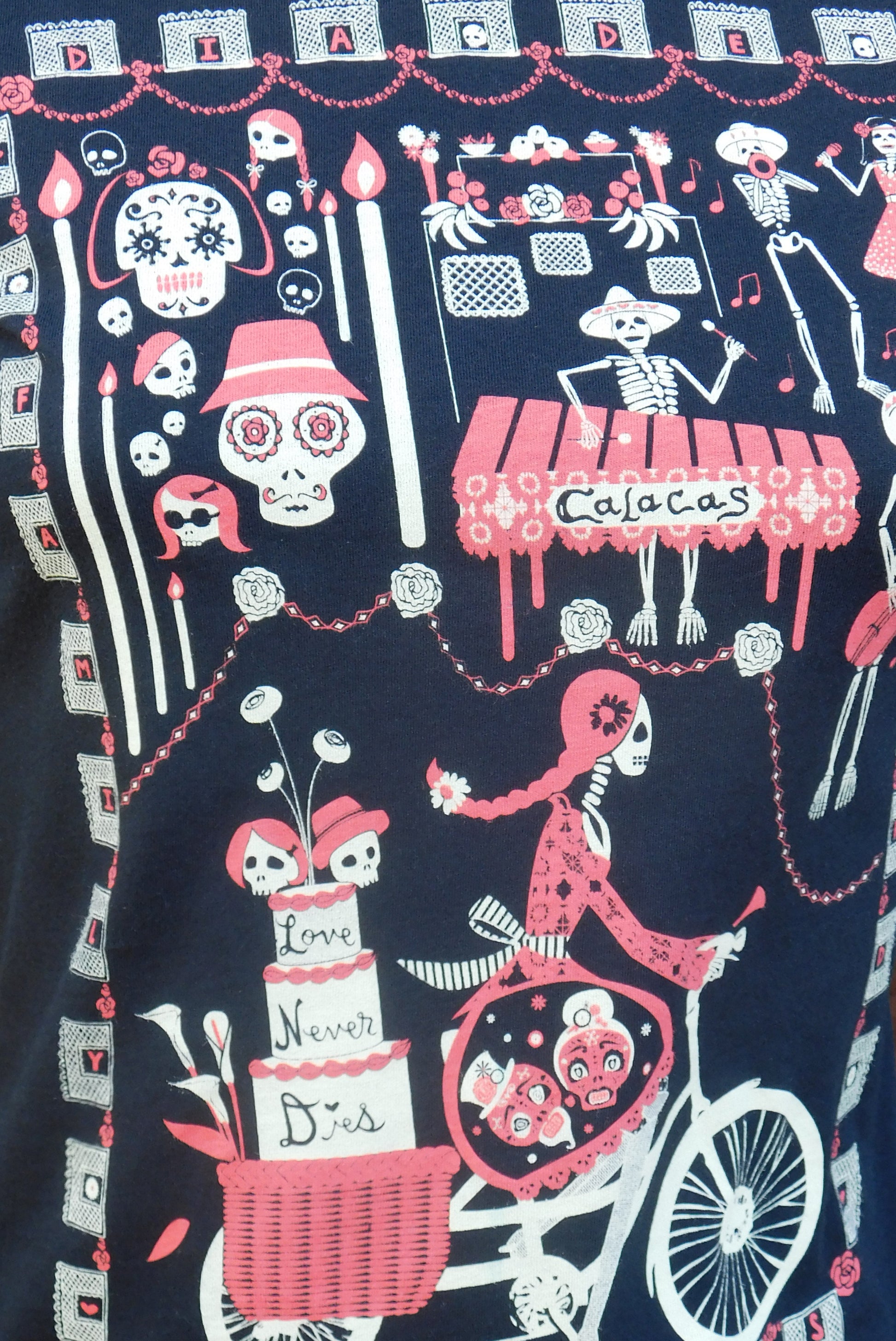 Closeup of fabric featuring graphic of skeletons celebrating and riding bikes