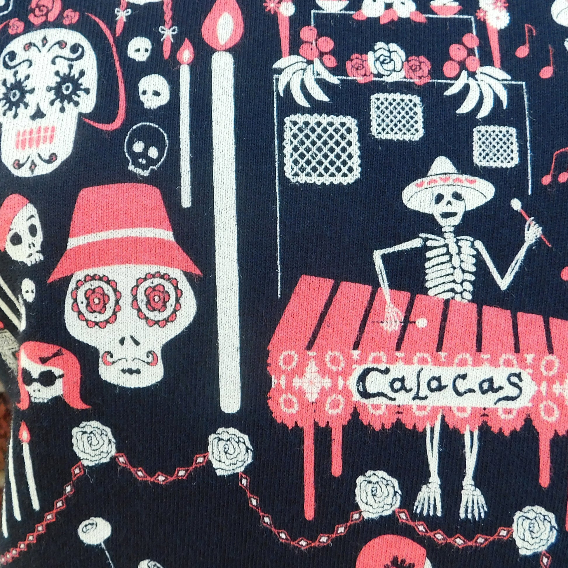 Closeup of fabric featuring graphic of skeletons celebrating and riding bikes
