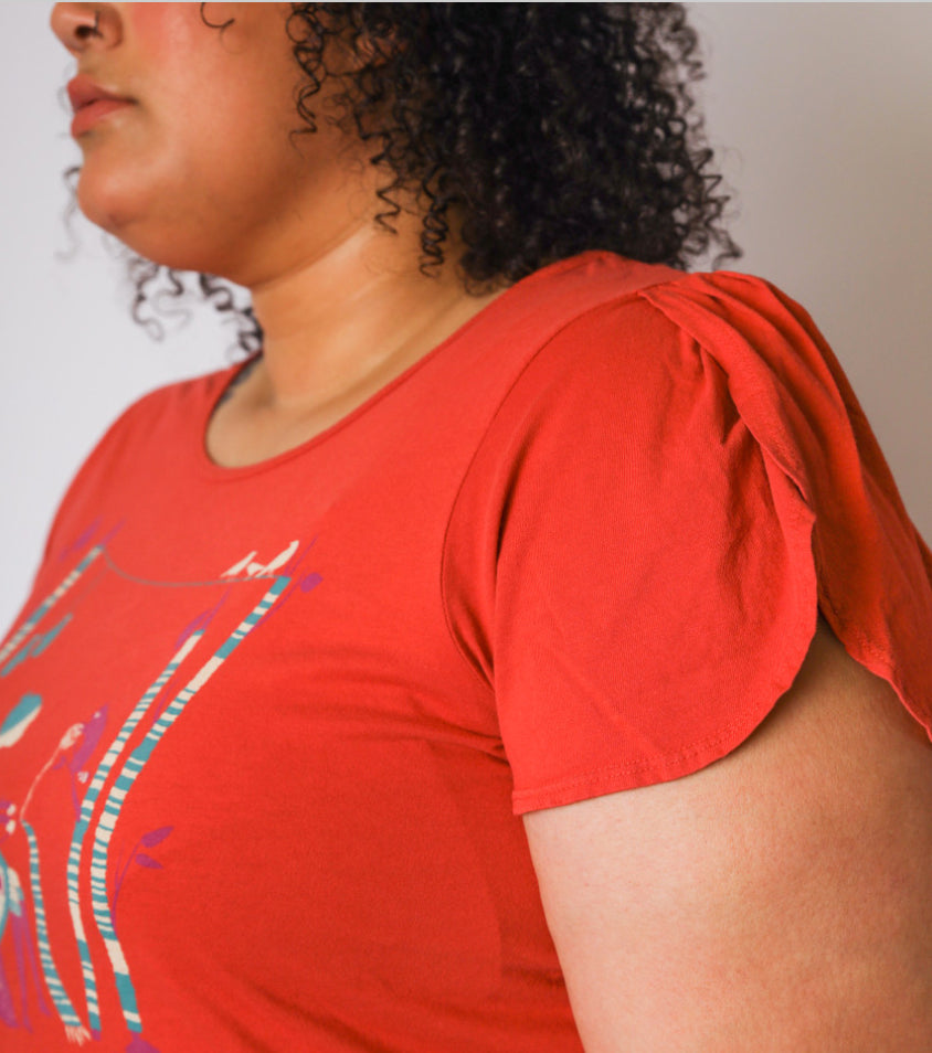 Side view of curly haired model with red t-shirt with knitting girl graphic