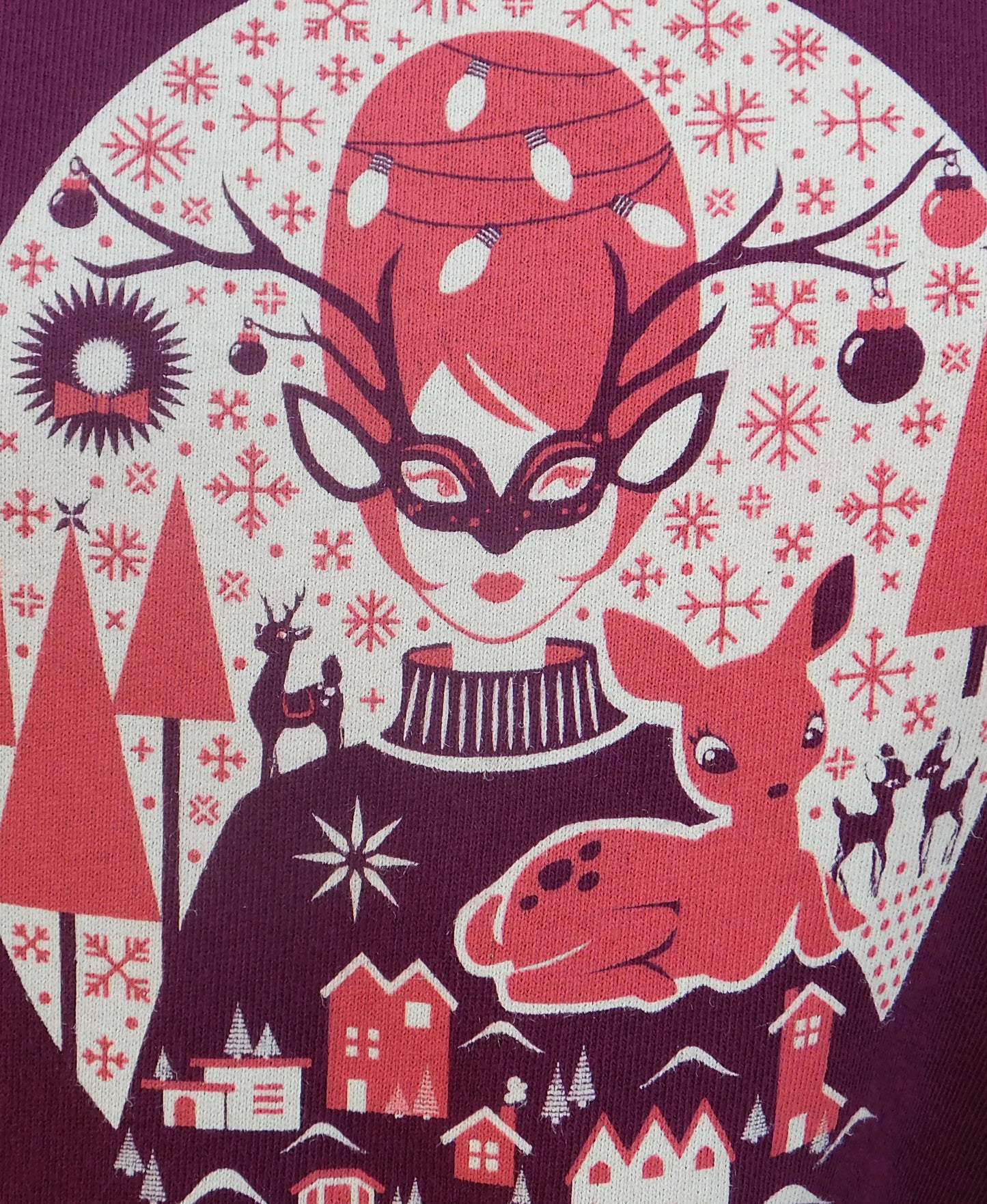 Closeup of Christmas sweater detail with girl, putz houses, deer, and wreath