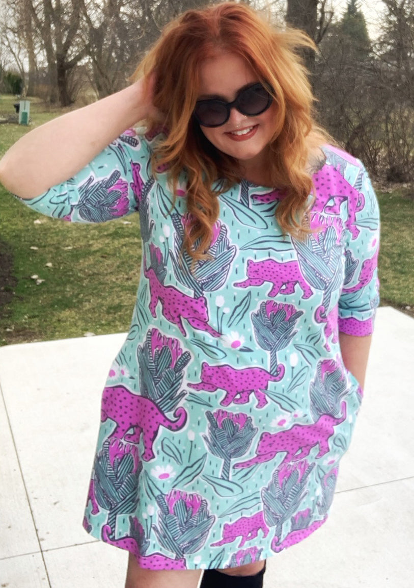 Red haired model in mint green and pink pocket tunic with a print of protea flowers and jaguars 