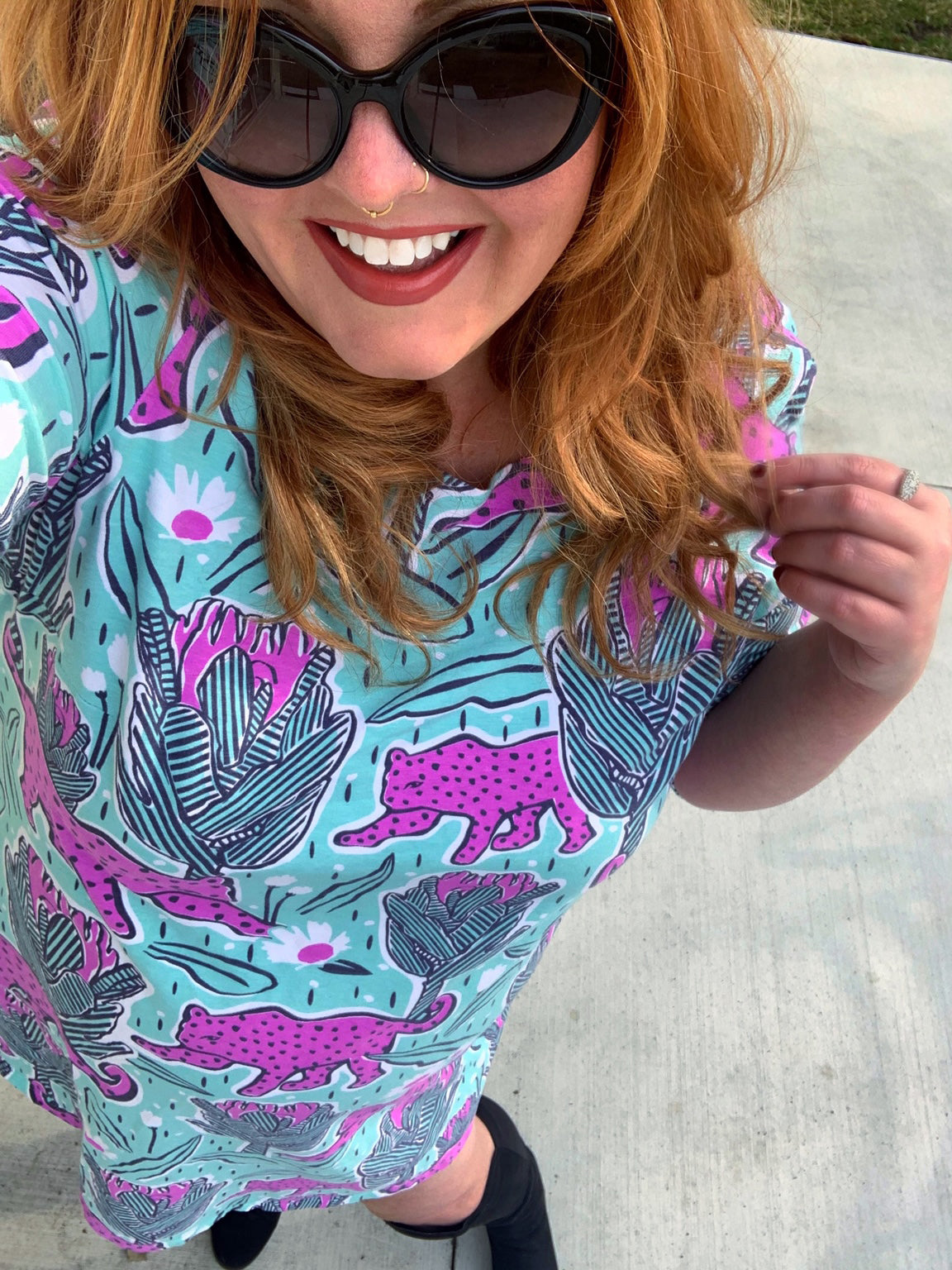 Red haired model in mint green and pink pocket tunic with a print of protea flowers and jaguars, closeup