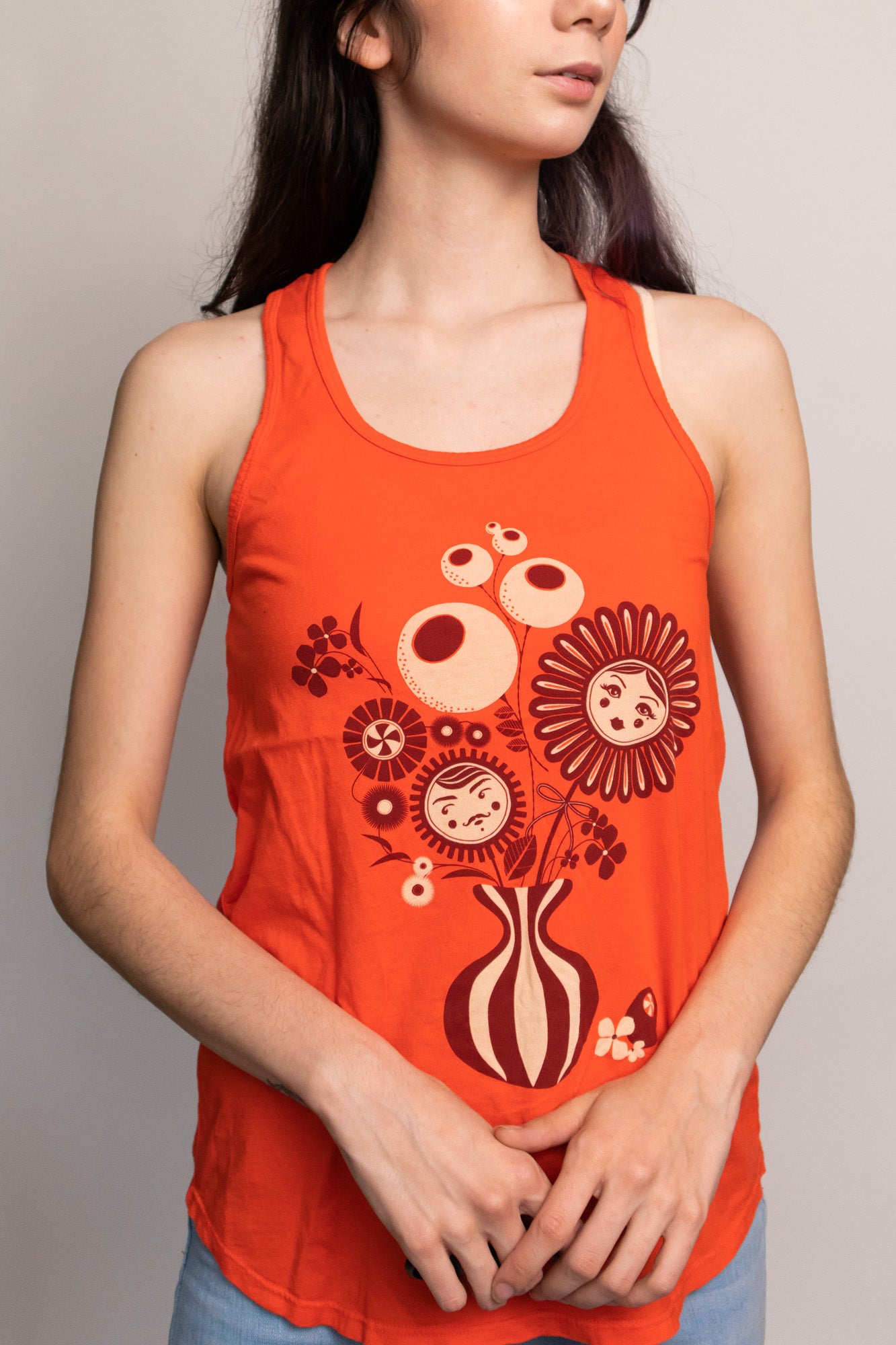 Bright orange tank top with print of flower vase on model 